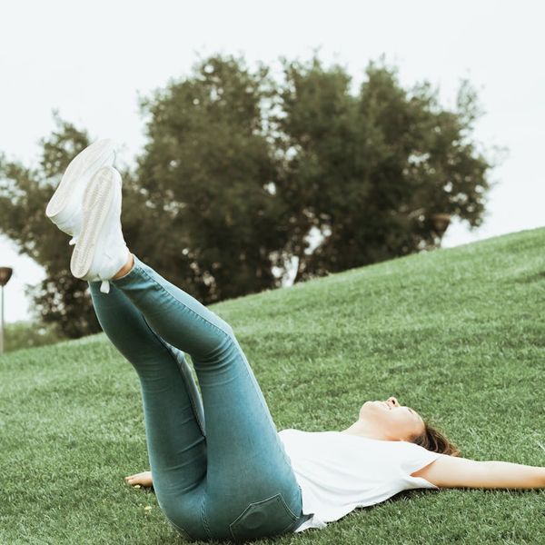 Woman smiling and stretching outdoors in a green park.